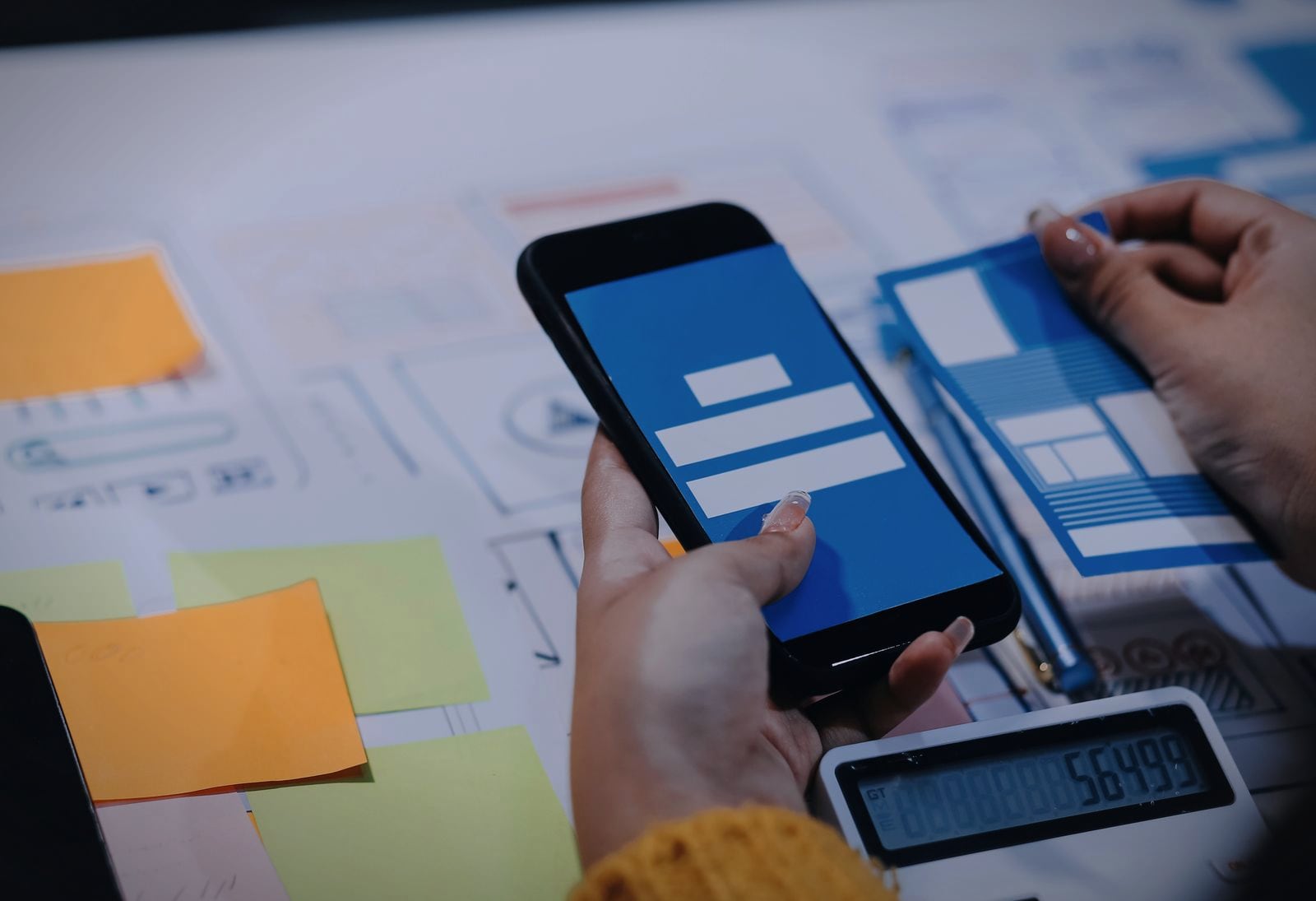A mobile app screen checked on a phone against paper wireframes