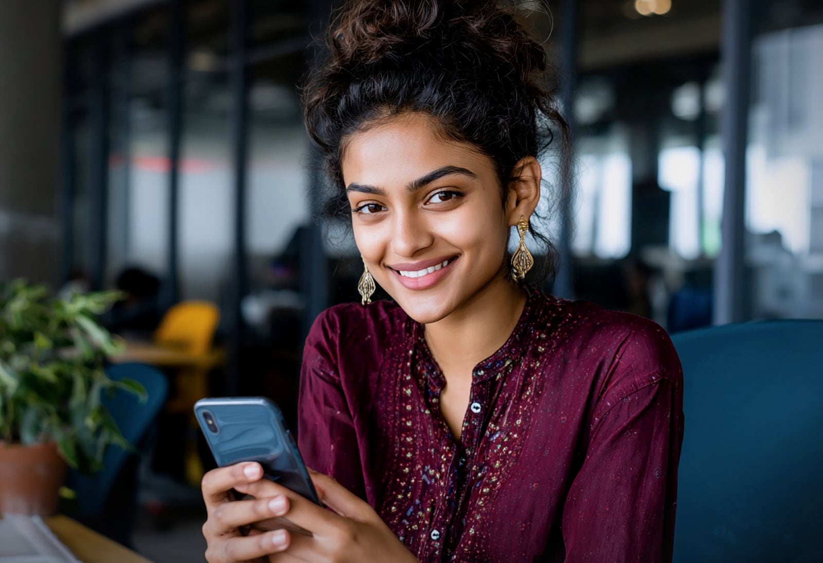 A young woman in India smiling at an app on her phone