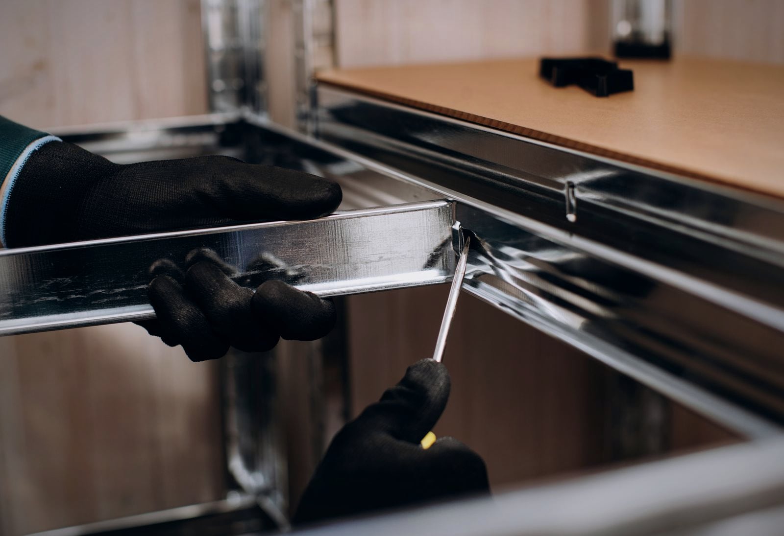 A fitter assembling a stainless shelving unit in a commercial kitchen