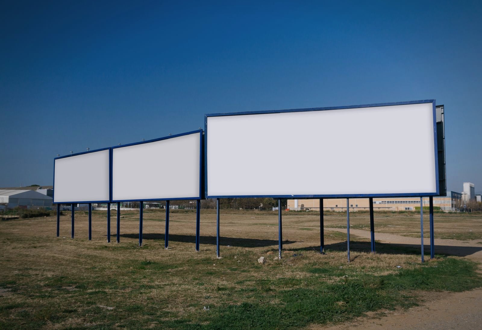Two blank hoardings standing side by side against the sky, the inventory an operator sells by the month
