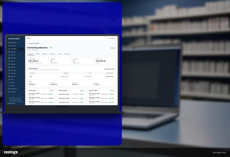 A laptop on a distributor counter in front of shelves showing the customer outstanding screen of the Sazinga Field portal.
