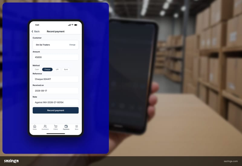 A depot worker in a warehouse holding a phone showing the payment-recording screen in Sazinga Field while registering a distributor.