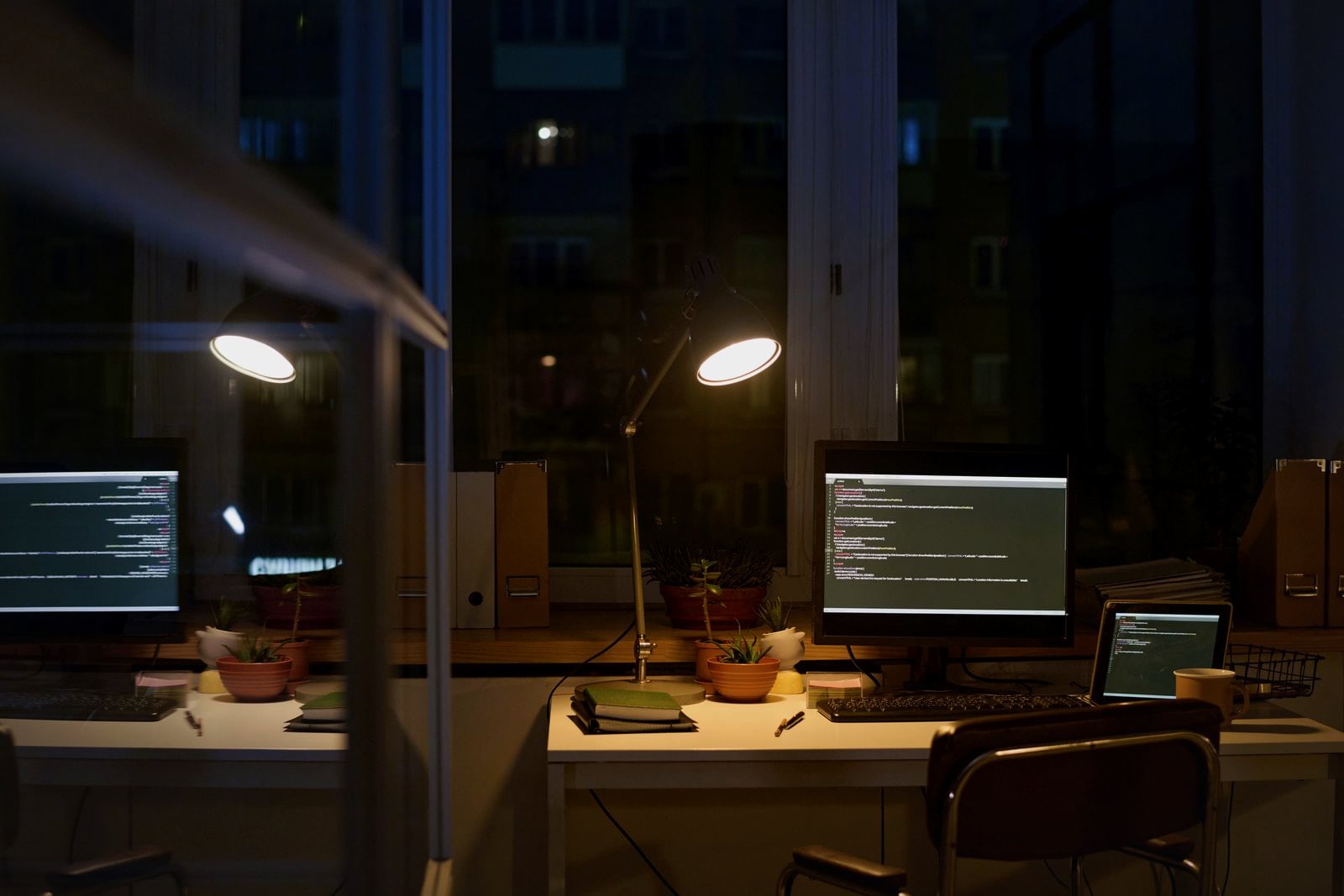 An engineering office at night with code on the monitors