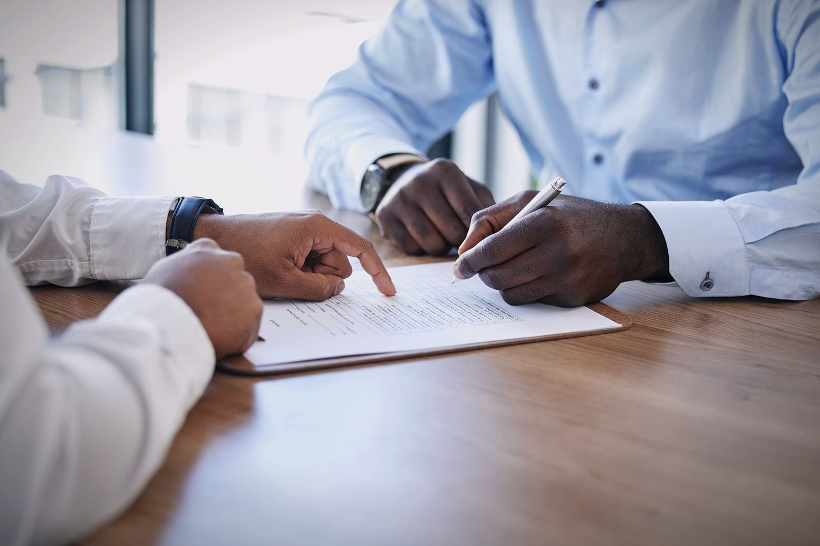 Two people going through a contract line by line at a table