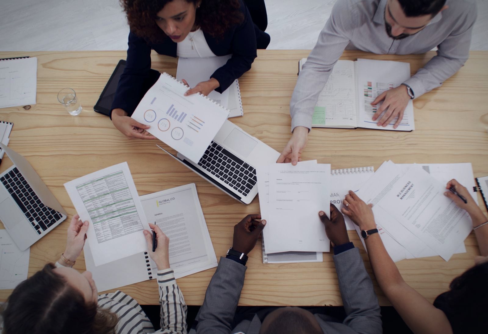 A team around a table working through paperwork and spreadsheets by hand