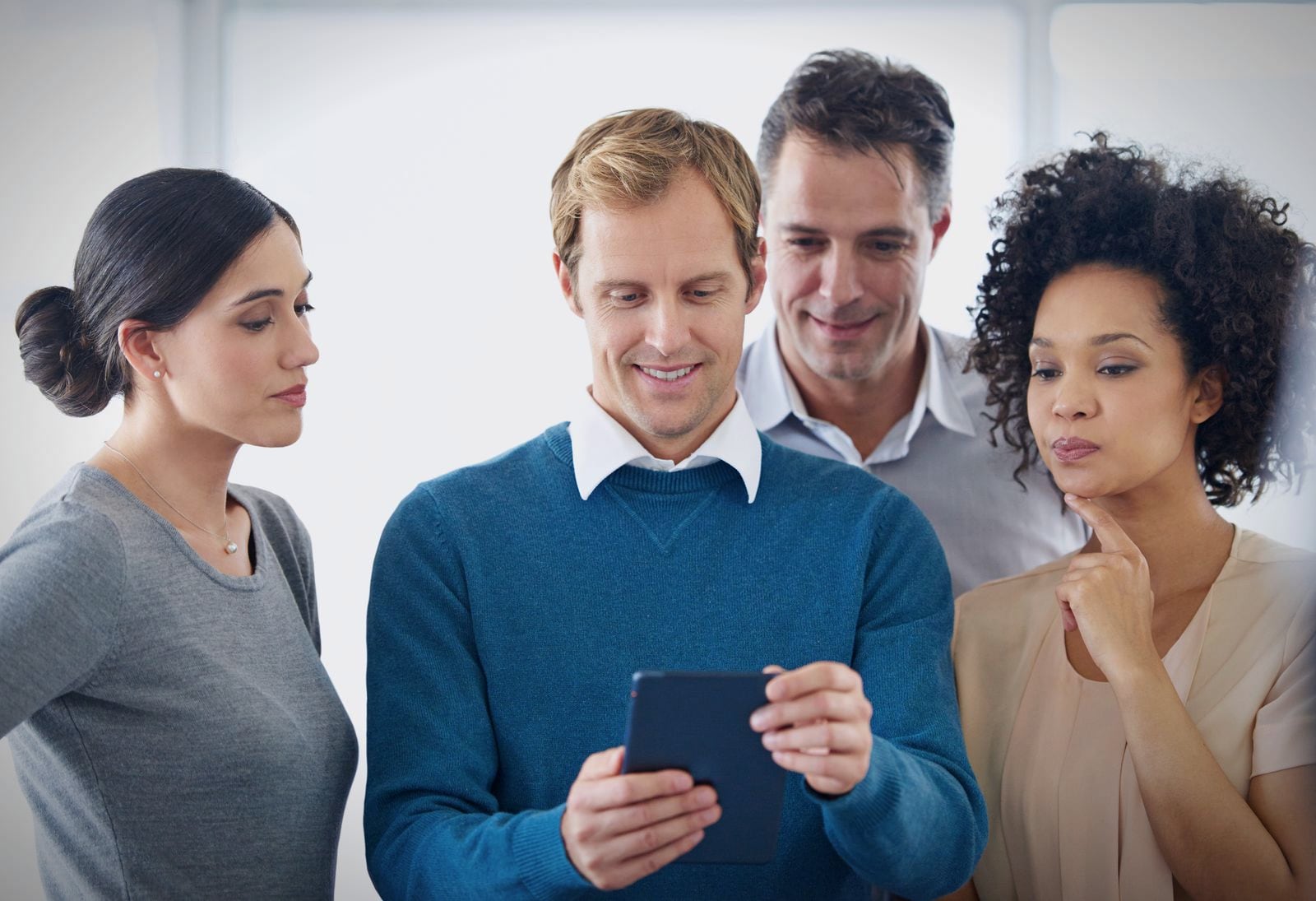 A small founding team gathered around a phone, watching a first user try the app